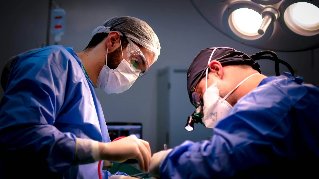Surgeon operating using healthcare analytics to help patient progress during recovery.